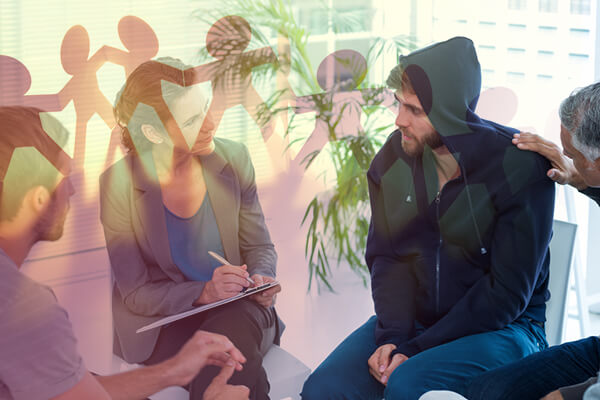 Group of people sitting in a sober living home discussing their recovery