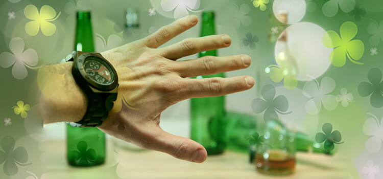 Hand with watch on blocking green beer bottles