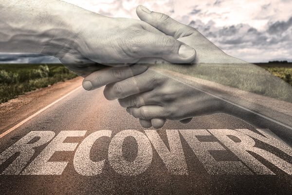 empty road with word "recovery" written over it and two hands lifting one up